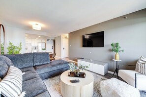 Ein modernes Wohnzimmer mit einer Eckcouch, einem runden Couchtisch und einem flachbildfernseher, der an der Wand montiert ist.