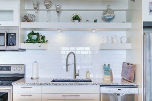 A modern kitchen with white cabinetry, a stainless steel refrigerator, a built-in microwave, and a double sink. - The Oslo - 2BD Downtown (Saskatoon)