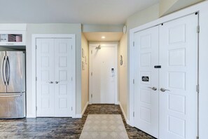 A hallway with white double doors, a stainless steel refrigerator, and a patterned rug on the floor. - The Oslo - 2BD Downtown (Saskatoon)