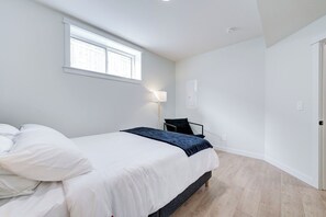 A bedroom with a bed, a window, a lamp, and a door.