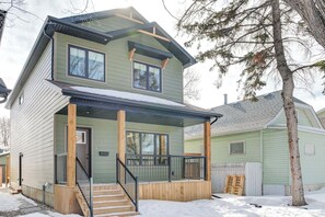 A two-story house with a front porch, a covered entryway, and a visible garage. - Hygge Hideaway –  Near the River (30 Nights +) (Saskatoon)
