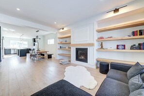 A modern living room with a fireplace, built-in shelves, and a dining area. - Hygge Haven – Stylish Stay near the River (Saskatoon)