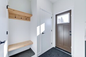 A hallway with a wooden bench, a white door, and a brown door with a window. - Hygge Haven – Stylish Stay near the River (Saskatoon)