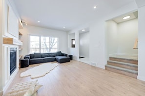 Amplia sala de estar con sofá modular, chimenea y escalera.