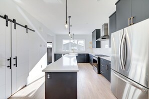 Una cocina moderna con una isla central, electrodomésticos de acero inoxidable y vistas al exterior.