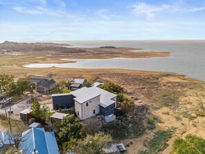 A residential area with a large body of water, houses with stone and metal roofs, and a clear sky. - Lake Buchanan Bliss | Pool & Spa • Lakefront Beach (Burnet)