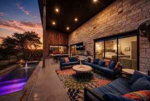 A modern outdoor living area with a stone wall, seating, and a pool. - Lake Buchanan Bliss | Pool & Spa • Lakefront Beach (Burnet)