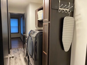 A laundry area with a washing machine, dryer, and ironing board. - Luxury 6BR Retreat - Spacious & Refined Living (Apple Valley)