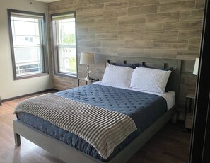A bedroom with a large bed, two bedside lamps, and a view through a window. - Luxury 6BR Retreat - Spacious & Refined Living (Apple Valley)