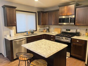 A modern kitchen with dark wood cabinets, a stainless steel range, and a granite countertop. - Luxury 6BR Retreat - Spacious & Refined Living (Apple Valley)