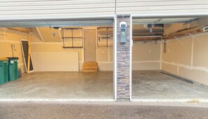A garage with a concrete floor, a wooden door, and a stone accent wall. - Luxury 6BR Retreat - Spacious & Refined Living (Apple Valley)