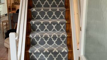 Una escalera con alfombra estampada, peldaños de madera y una puerta blanca con panel de vidrio.