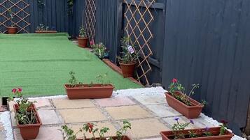 A garden with potted plants arranged on a stone patio.