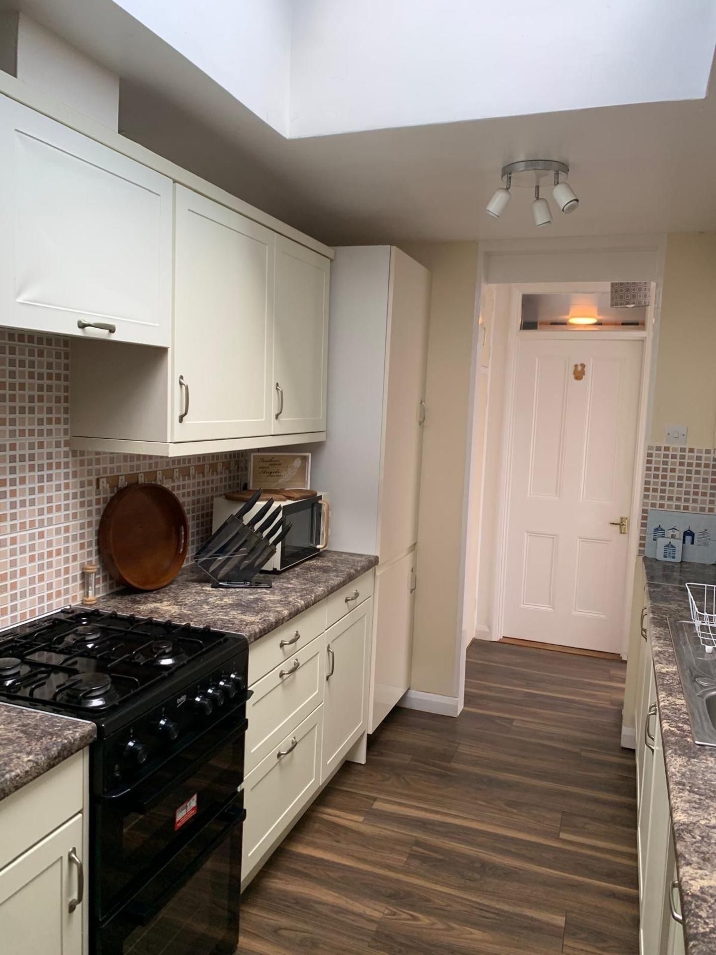 A kitchen with white cabinets, a stove, and a tiled backsplash.