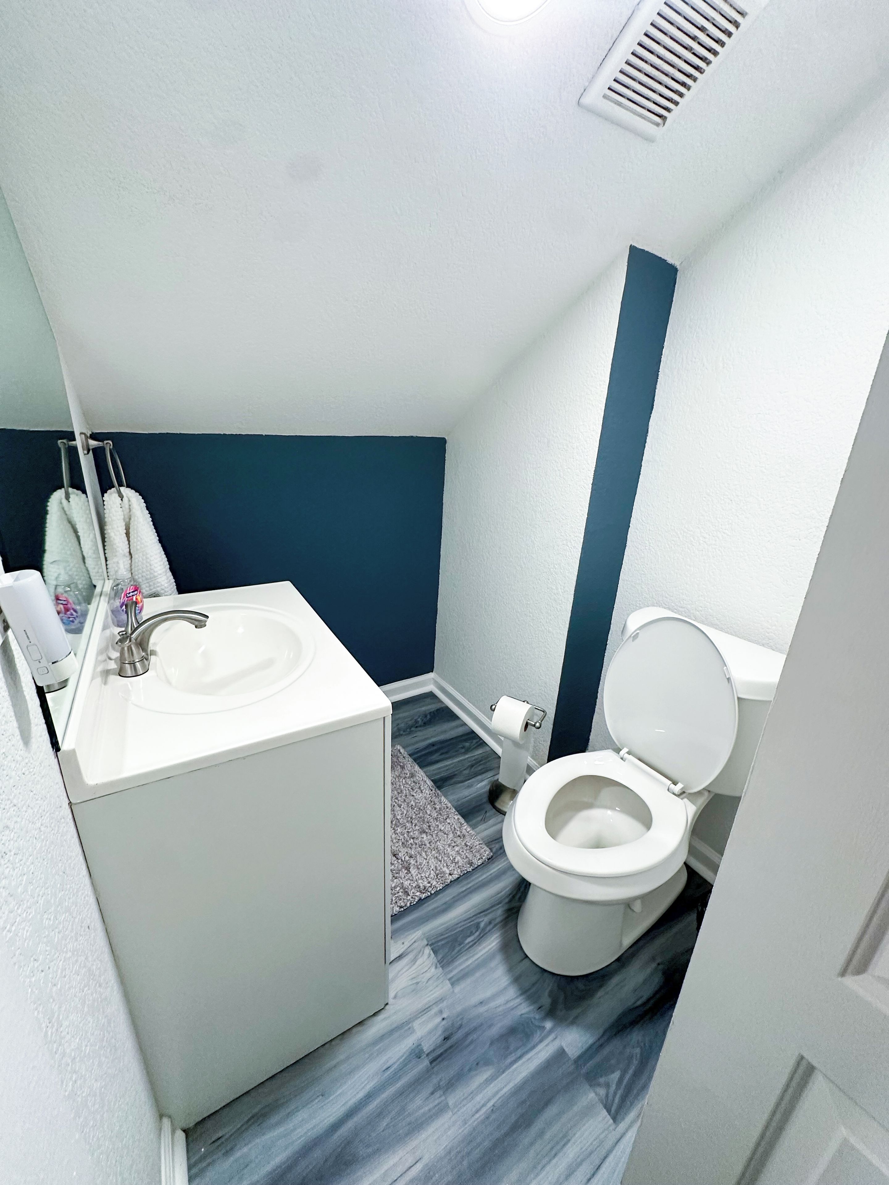 Un bagno con un lavandino bianco, un water e una parete decorata in blu.