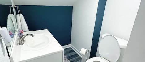 Un bagno con un lavandino bianco, un water e una parete decorata in blu.