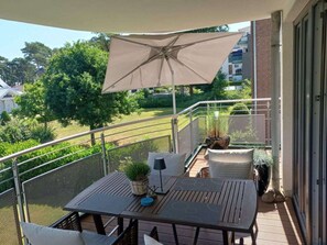 A balcony with a table, chairs, a potted plant, and an umbrella. - Residence by the sea - Strandallee 178 (Timmendorfer Strand)