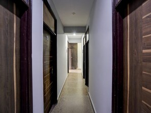 A corridor with wooden doors on either side, leading to a room with a visible door at the end. - Deluxe With Balcony The Cloud inn Hotel Grand (Ghaziabad)