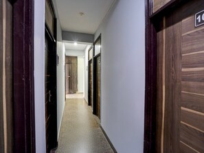 A hallway with wooden doors, a tiled floor, and a ceiling light. - Deluxe With Balcony The Cloud inn Hotel Grand (Ghaziabad)