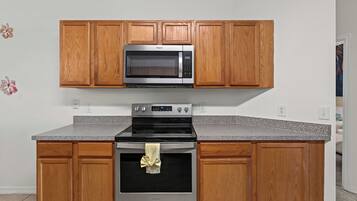 A kitchen with wooden cabinets, a stainless steel microwave, and a built-in oven.