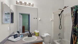 Un baño con lavabo, espejo, tocador, inodoro y ducha.