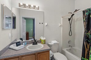 Ein Badezimmer mit Waschbecken, Spiegel, Waschtisch, Toilette und Dusche.