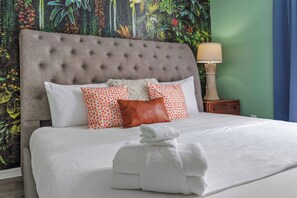 A neatly made bed with white linens and a grey tufted headboard, accompanied by a variety of pillows, including a white one and two with orange polka dots. - Hidden Lagoon: 5-Bedroom House with Private Pool Close to Disney & Theme Parks (Davenport)