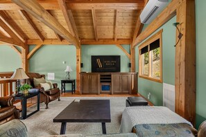 A cozy living room with a wooden ceiling, a flat-screen TV, a sofa, a coffee table, and a fireplace. - Lakeview Lodge | Hot Tub | Beach Access | Fire Pit (Invermere)