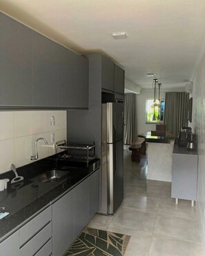 A modern kitchen with a stainless steel refrigerator, a built-in oven, and a black countertop. - CJ17GIL -3D -Arraial D’ajuda/Piscina/ Beach Tennis (Arraial da Ajuda)
