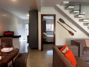 Ein modernes Wohnzimmer mit Essbereich, einer Treppe und Blick in einen weiteren Raum.