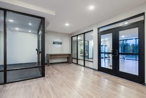 Un moderno vestíbulo de hotel con puertas de vidrio, un banco y un cartel con el nombre del hotel.
