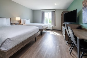 Habitación de hotel con dos camas, un escritorio con silla, televisor y ventana con cortinas.