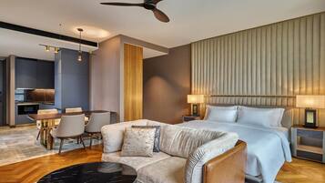 Een moderne hotelkamer met een bed, een bank, een eettafel en een plafondventilator.