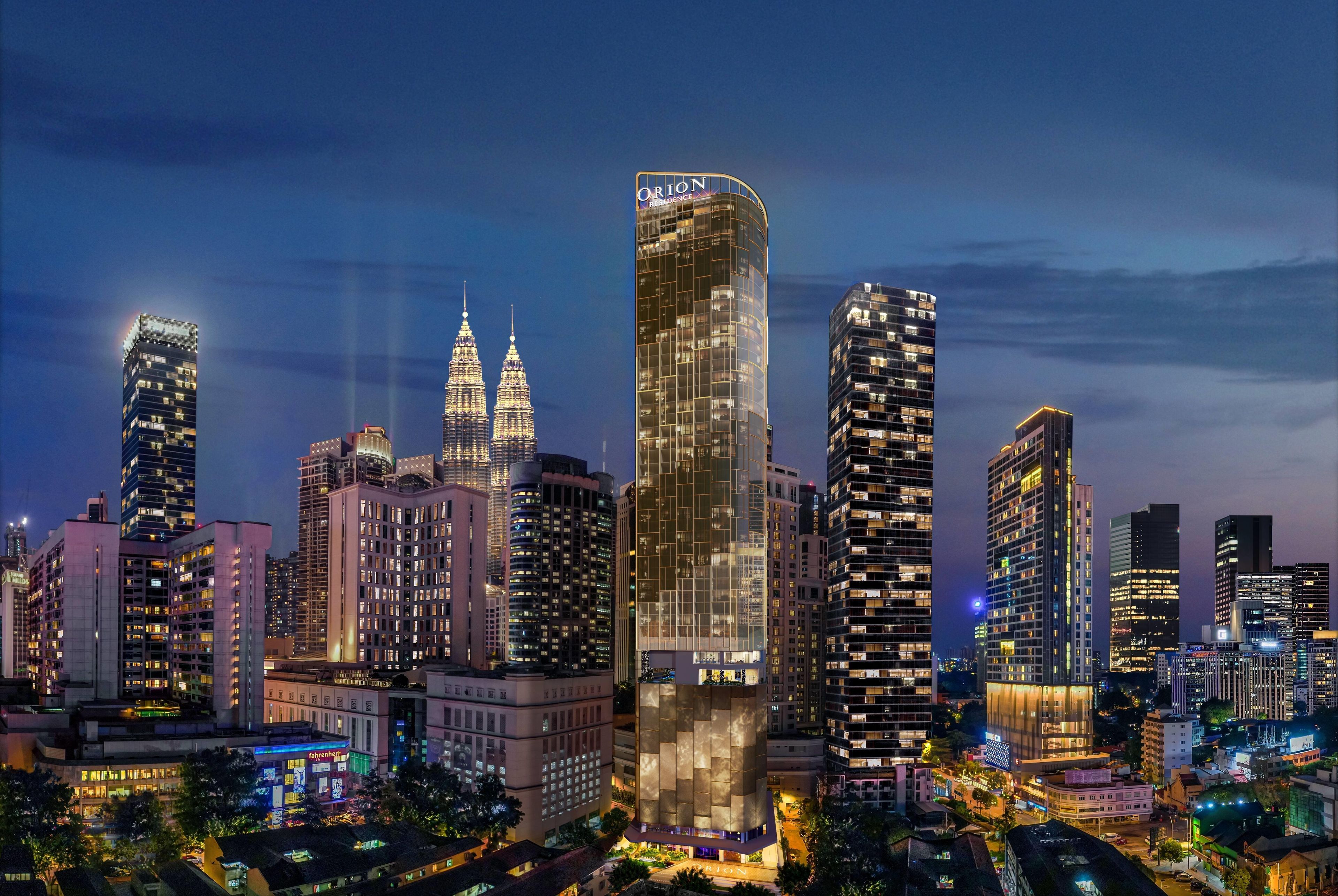 A cityscape at night with prominent skyscrapers, including the Petronas Towers.