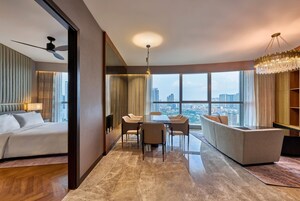 Una habitación de hotel con una cama, una zona de comedor con mesa y sillas, un sofá, un ventanal con vista a la ciudad y un ventilador de techo.