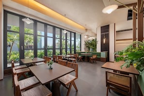 A modern restaurant interior with large windows, wooden furniture, and indoor plants. - Days Hotel By Wyndham Nanchang West Station (Nanchang)