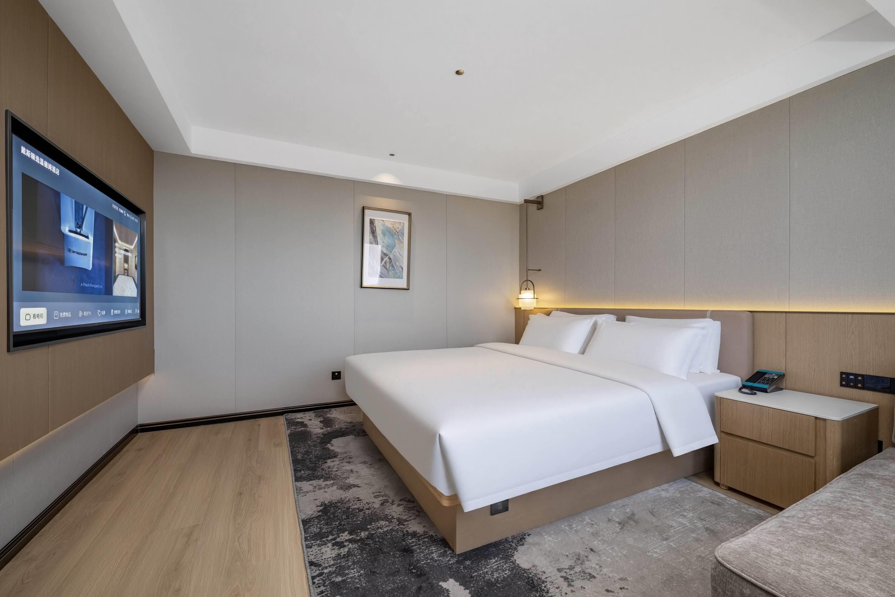 Habitación de hotel con una cama grande, mesitas de noche, un televisor de pantalla plana y un cuadro en la pared.