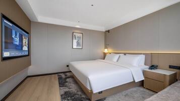 Habitación de hotel con una cama grande, mesitas de noche, un televisor de pantalla plana y un cuadro en la pared.