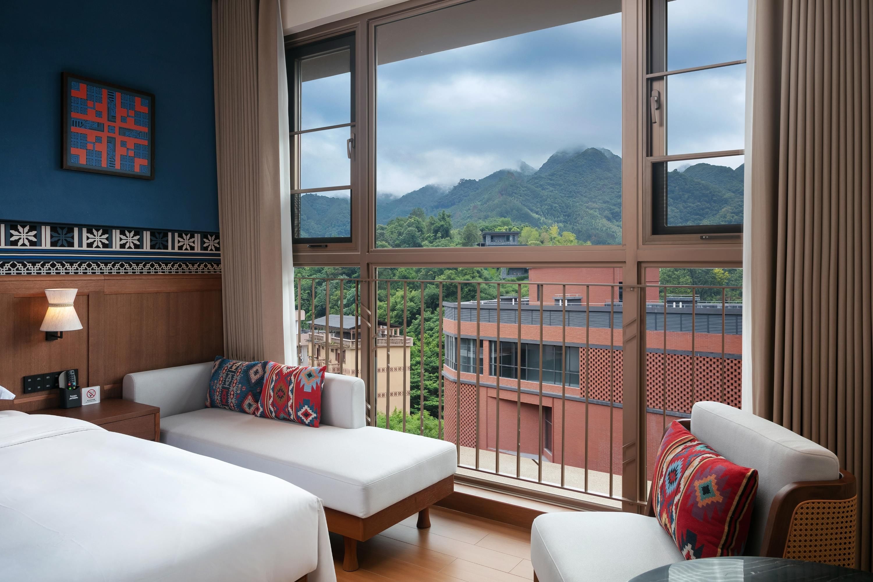 Une chambre d’hôtel avec un balcon, un lit, un canapé et une vue sur les montagnes.