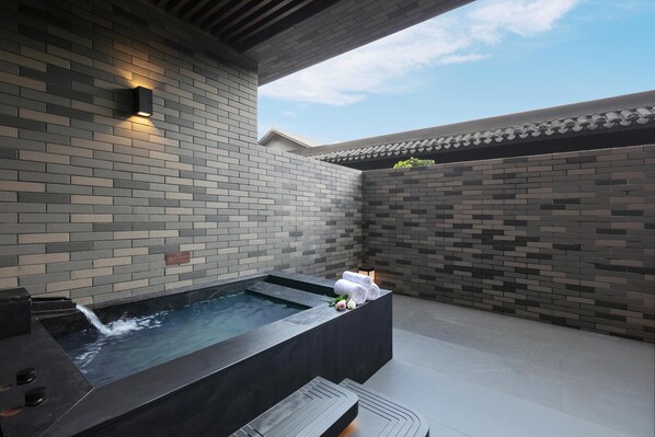 A spa area with a hot tub, a bench, and a wall with a tiled pattern.