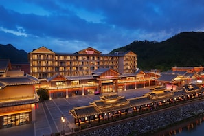A hotel with multiple buildings, a large sign reading 'RAMADA BY WYNDHAM,' and traditional architectural elements.