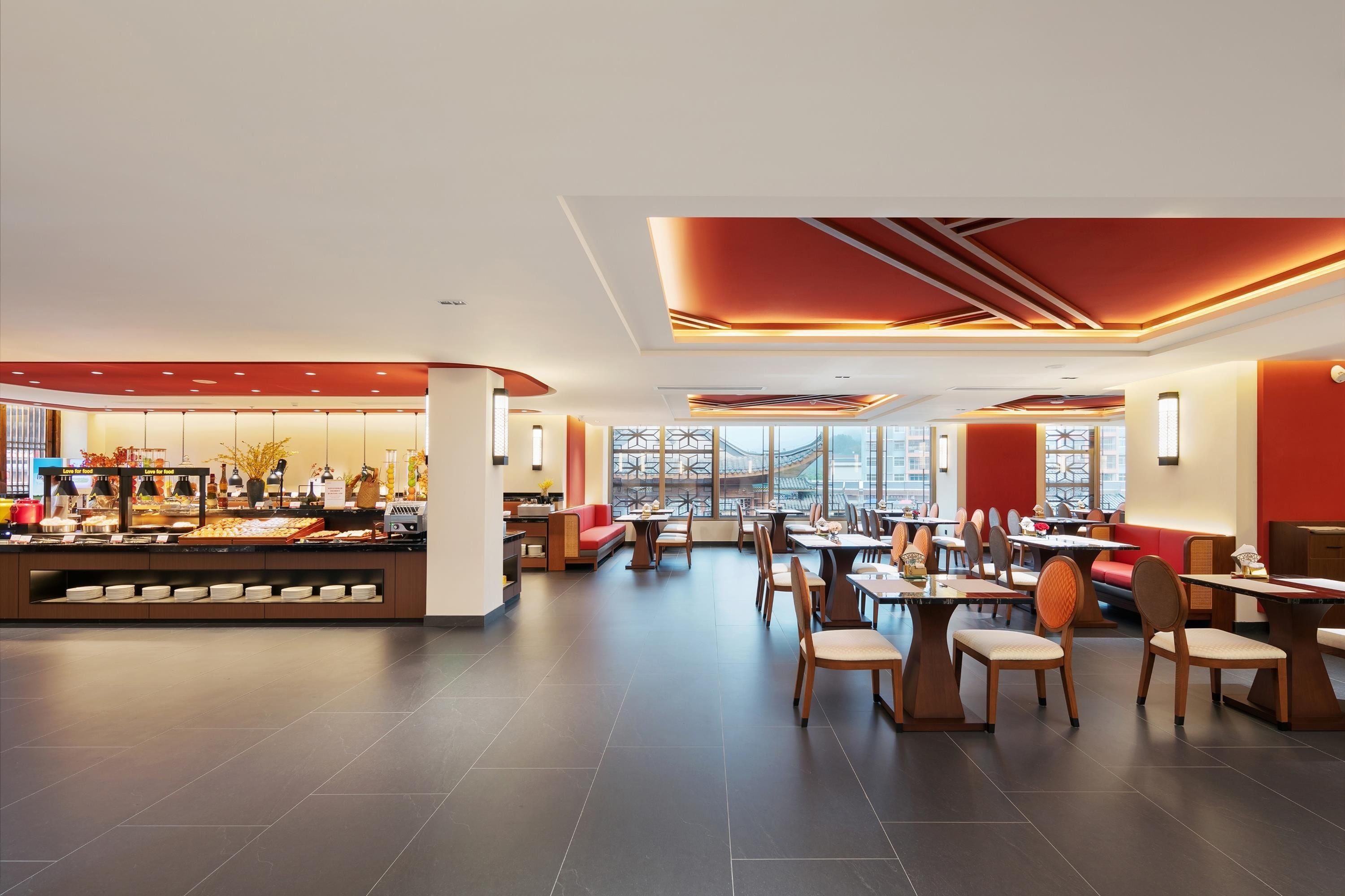 A modern dining area with a buffet, seating arrangements, and a view of the cityscape through large windows.