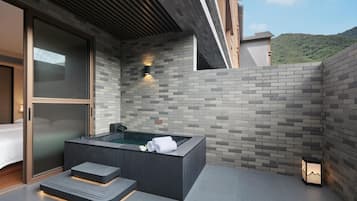 Un moderno espacio exterior con spa, que incluye una bañera de hidromasaje, asientos y vistas a un paisaje montañoso.