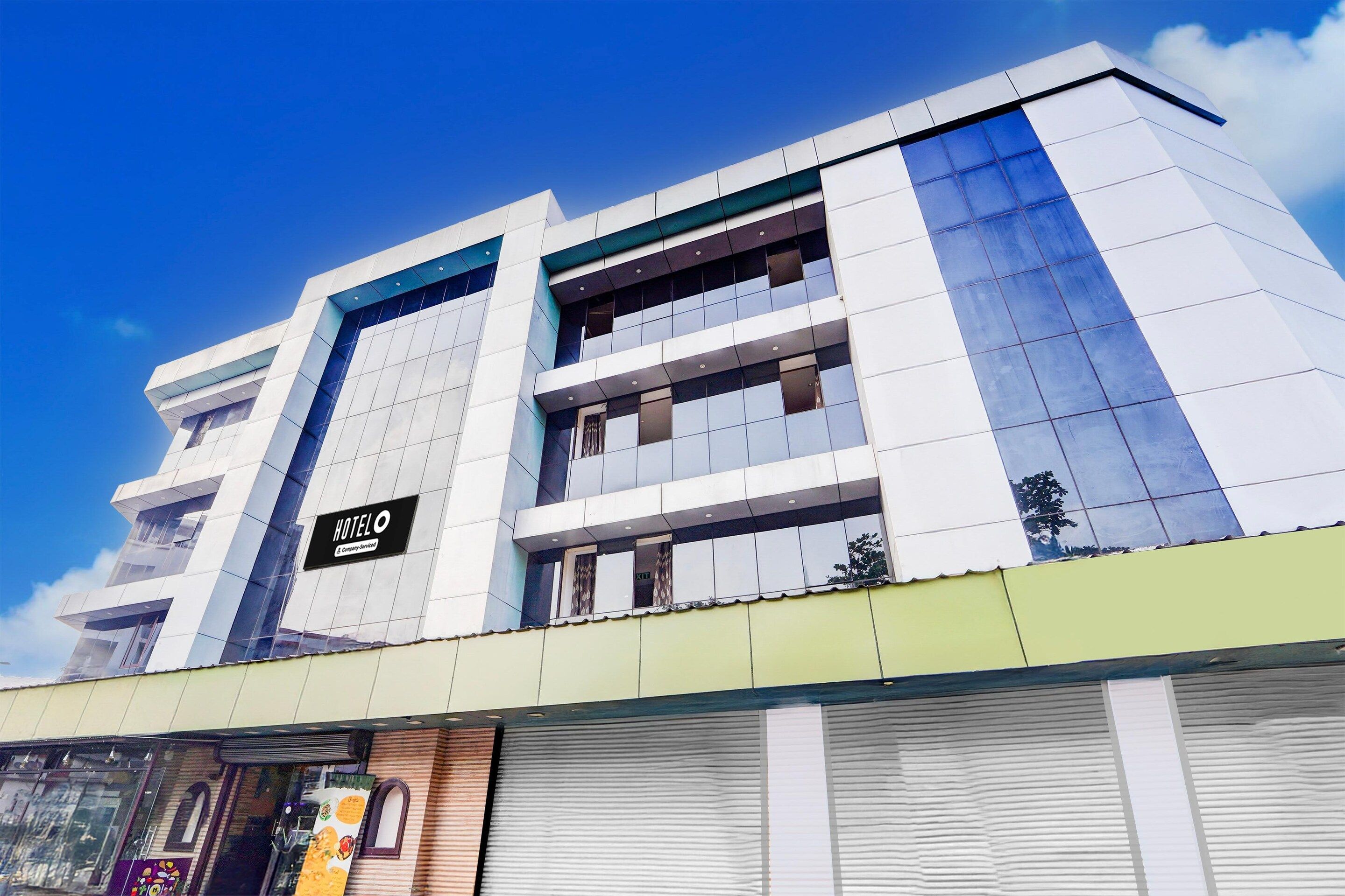 A modern hotel building with a prominent 'HOTEL O' sign, multiple floors, and a green awning.