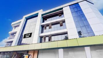 A modern hotel building with a prominent 'HOTEL O' sign, multiple floors, and a green awning.