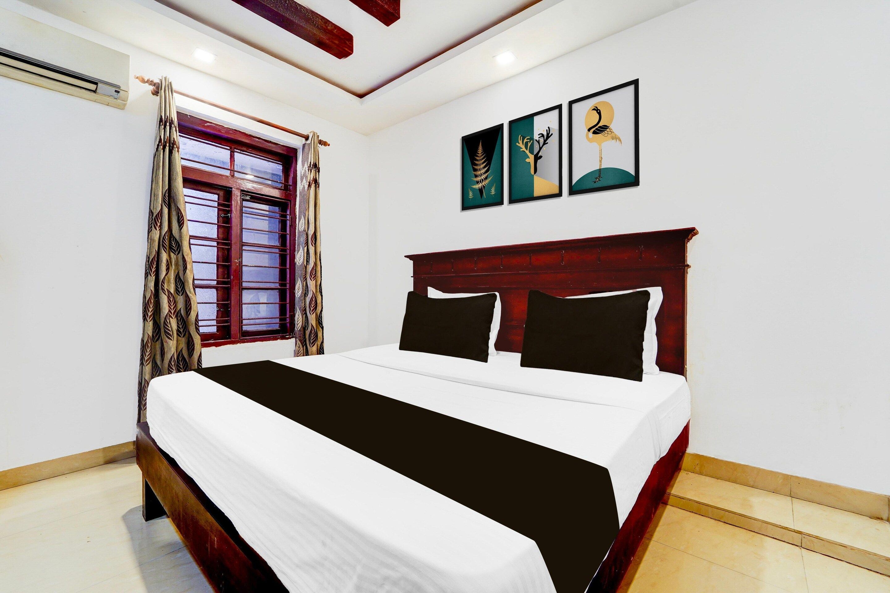 A bedroom with a bed, a window with curtains, and wall art.