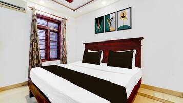 A bedroom with a bed, a window with curtains, and wall art.