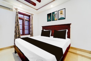 A bedroom with a bed, a window with curtains, and wall art. - Hotel O DH Road Ernakulam (Kanayannur)
