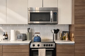 A kitchen with stainless steel appliances, a toaster, a kettle, and a range hood. - The Bentley Collection - The Sinclair (Dallas)