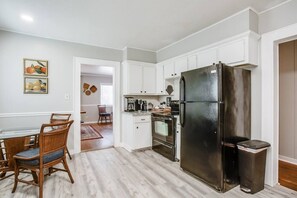 Eine moderne Küche mit weißen Schränken, einem schwarzen Kühlschrank und einem Essbereich mit Holzkästen.